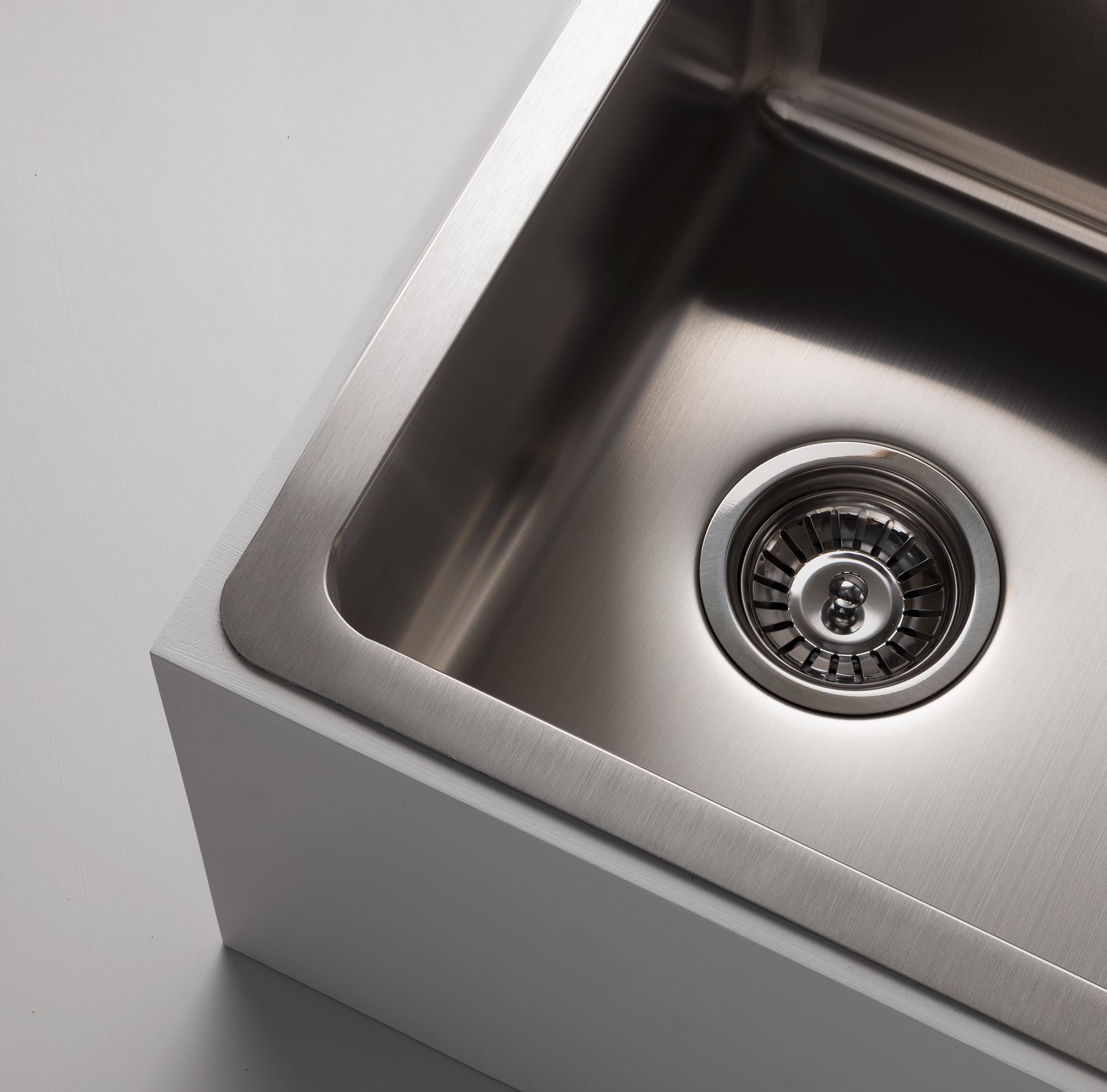 Close-up studio image of a Titan medium bowl sink in stainless steel, set against a gray background, highlighting the sleek design of the stainless steel sink.