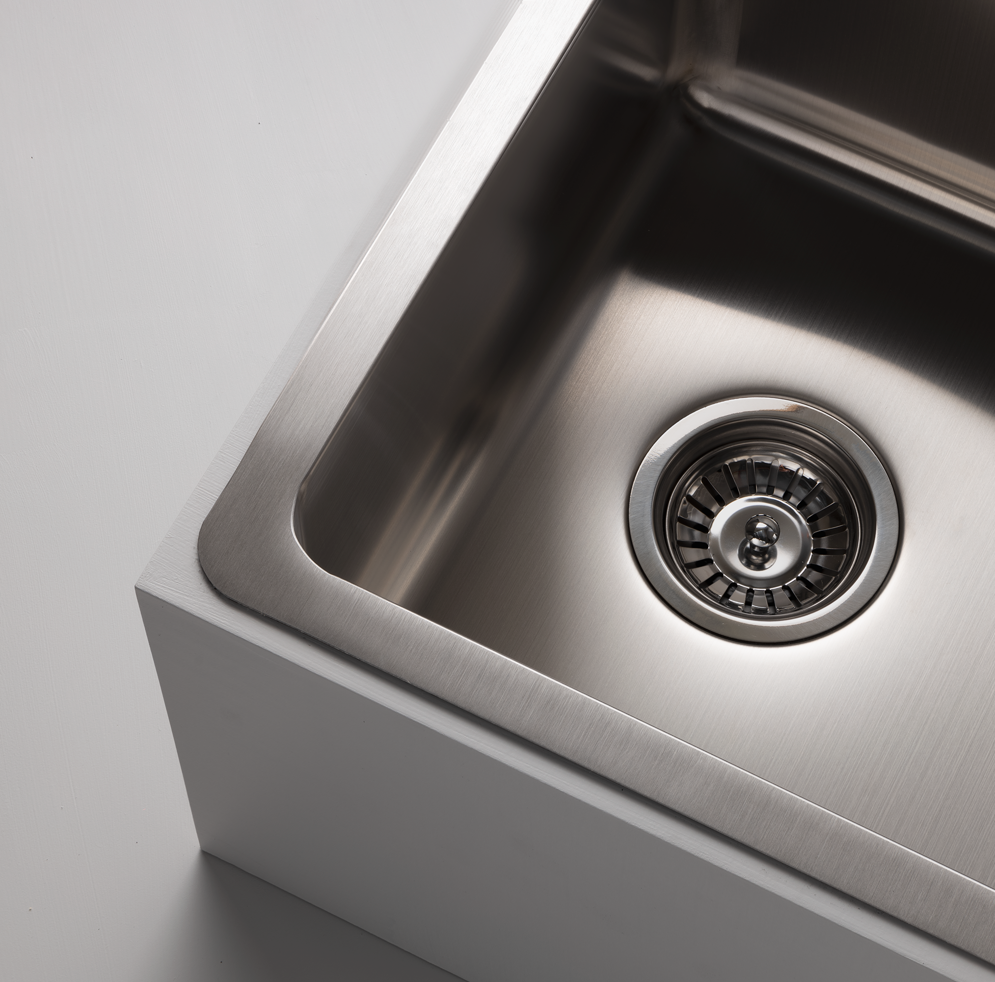 Close-up studio image of a Titan medium bowl sink in stainless steel, set against a gray background, highlighting the sleek design of the stainless steel sink.