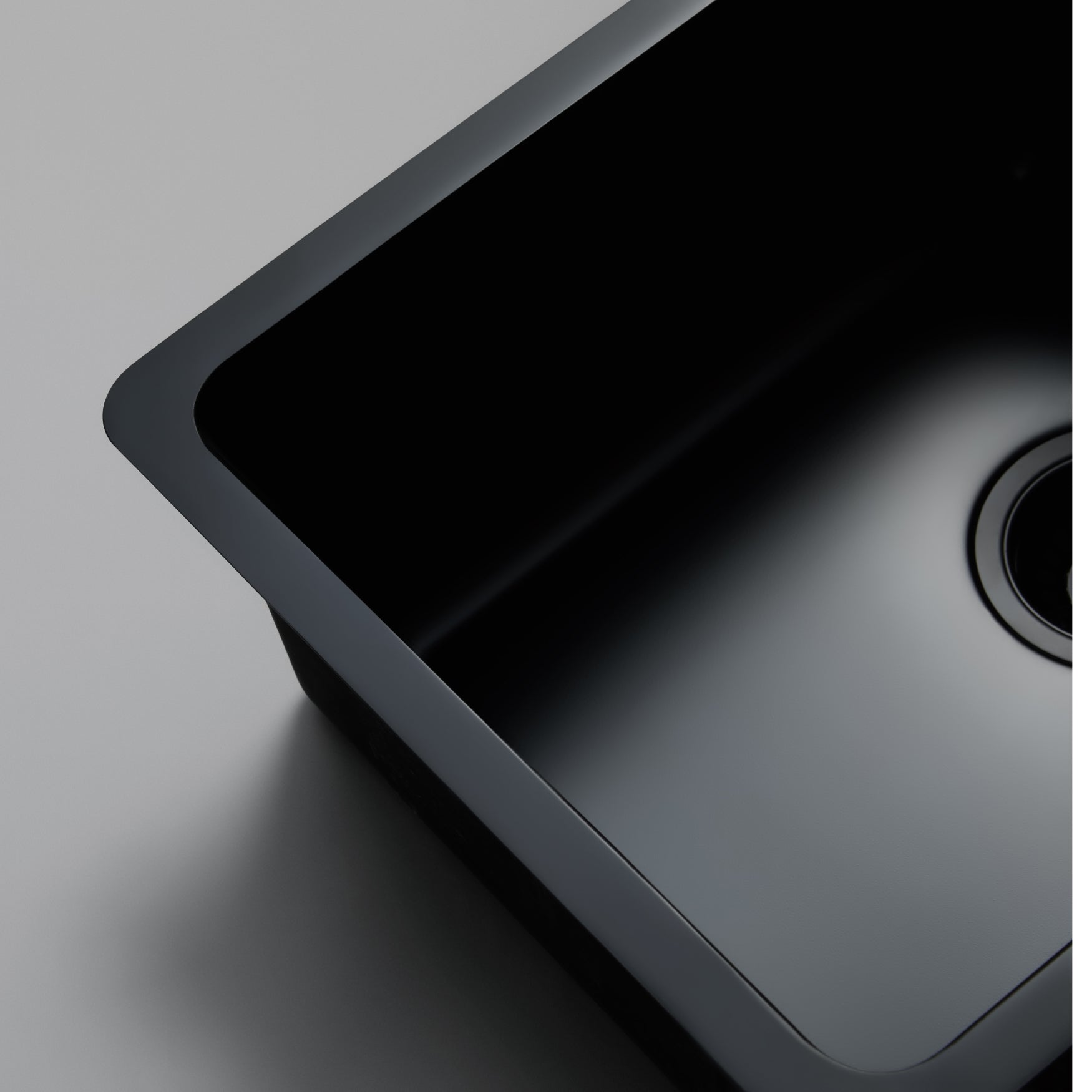 Close-up still life image of a Titan large bowl matte black kitchen sink against a gray background, highlighting the elegant design of the brass sink.